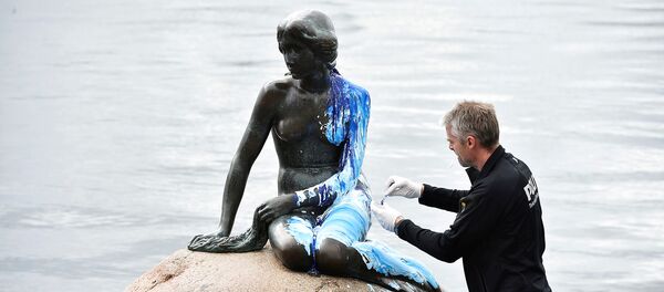 A police officer inspects the Little Mermaid statue, seen covered in paint, for the second time in weeks, in what local authorities say is an act of vandalism, in Copenhagen, Denmark June 14, 2017 - Sputnik International