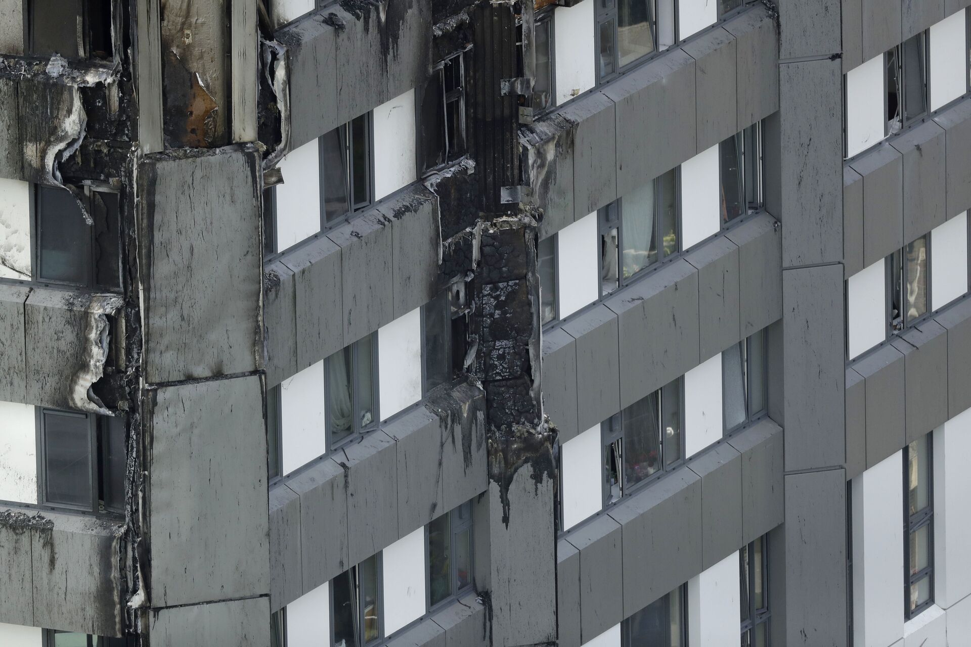 Fire damaged cladding is seen on the lower floors of the fire-gutted Grenfell Tower in London, Friday, June 16, 2017, after a fire engulfed the 24-story building Wednesday morning - Sputnik International, 1920, 10.09.2021