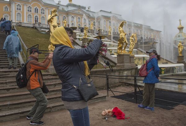 Tourists pose for photographs against the background of the Grand Cascade fountains during the opening of the summer season at the Peterhof museum-reserve - Sputnik International