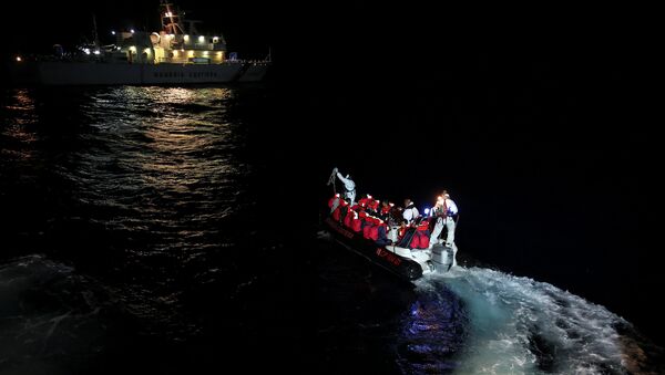 Fiorillo Italian Coast Guard vessel officers transfer migrants being rescued by Save the Children NGO crew from the ship Vos Hestia, in the Mediterranean sea off the Libyan coast, June 16, 2017 - Sputnik International
