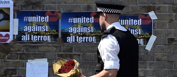 A police officer carries flowers to leave alongside of messages near to where a van was driven at muslims in Finsbury Park, North London, Britain, June 19, 2017 A police officer carries flowers to leave alongside of messages near to where a van was driven at muslims in Finsbury Park, North London, Britain, June 19, 2017 - Sputnik International