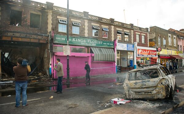 A police officer sets up a cordon around a burnt-out shop on High Road in Tottenham, north London on August 7, 2011.  - Sputnik International