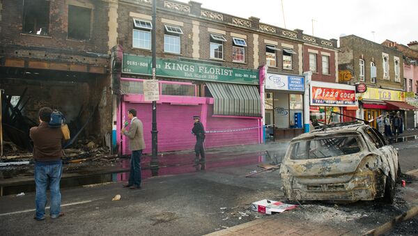 A police officer sets up a cordon around a burnt-out shop on High Road in Tottenham, north London on August 7, 2011.  - Sputnik International