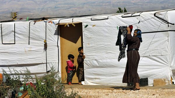 A Syrian refugee woman hangs laundry outside her tent at a Syrian refugee camp in the eastern city of Baalbek, Lebanon, Tuesday, June 20, 2017 - Sputnik International