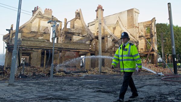 A policeman walks past the charred remains of the Reeves furniture store in Croydon, south of London, on August 9, 2011, following a third night of violence on the streets of London. - Sputnik International