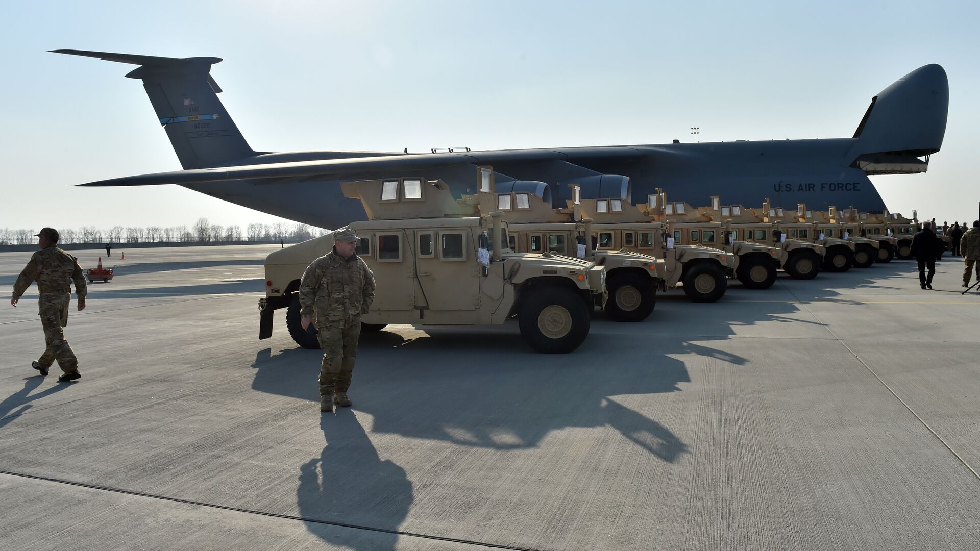 Ukrainian servicemen walk in front of armoured cars at Kiev airport on March 25, 2015 during a welcoming ceremony of the first US plane delivery of non-lethal aid, including 10 Humvee vehicles. - Sputnik International, 1920, 25.08.2022