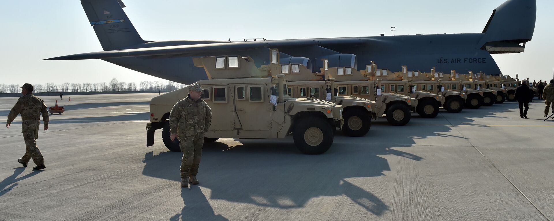 Ukrainian servicemen stroll in front of armored cars at Kiev airport on March 25, 2015 during a welcoming ceremony of the first US plane delivery of non-lethal aid, including 10 Humvee vehicles. - Sputnik International, 1920, 16.04.2024