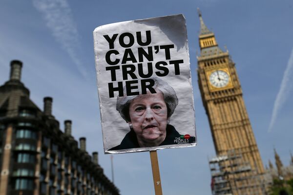 A placard showing a picture of Britain's Prime Minister Theresa May, saying You can't trust her is raised in front of the Elizabeth Tower, commonly referred to as Big Ben as protesters gather in Parliament Square after marching through central London on June 21, 2017. - Sputnik International
