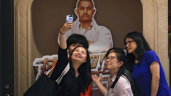 Chinese women take a selfie with a poster of Indian Bollywood blockbuster film Dangal on display at a cinema in Beijing. - Sputnik International