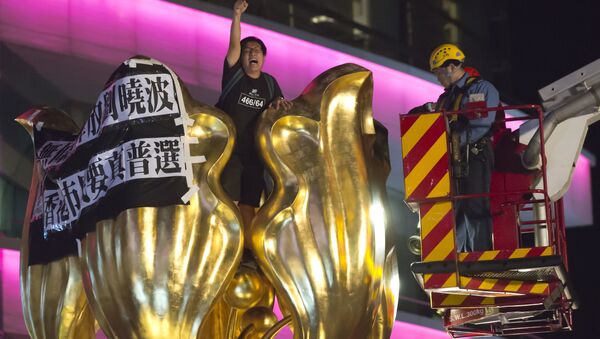 A police officer and a fireman try to remove a pro-democracy activist who shouts slogan and hangs a cloth that reads Release Liu Xiaobo unconditionally, Hong Kong people want genuine universal suffrage, on a giant flower statue bequeathed by Beijing in 1997 in Golden Bauhinia Square of Hong Kong Wednesday, June 28, 2017. - Sputnik International
