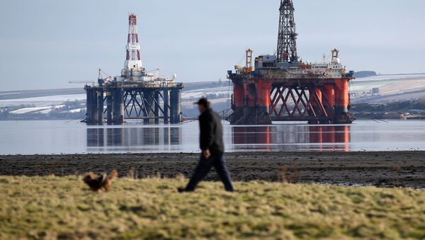In this Monday Feb. 15, 2016 photo, a man walks past oil platforms laid-up in the Cromarty Firth near Invergordon in the Highlands of Scotland. North Sea oil has passed its zenith in terms of production as the recent plunge in energy prices forces oil companies to rethink investment in fields that were already in decline. - Sputnik International