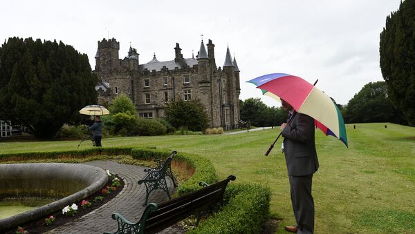 A journalist waits in the rain outside Stormont Castle in Belfast, Northern Ireland June 29, 2017. - Sputnik International