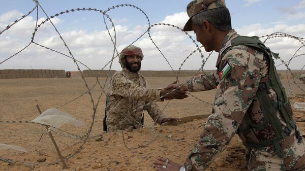 A member of the Syrian Tribes Army, left, that guards the Syrian side of the berm on the north eastern border with Jordan, shakes hands with a Jordanian soldier (File) - Sputnik International