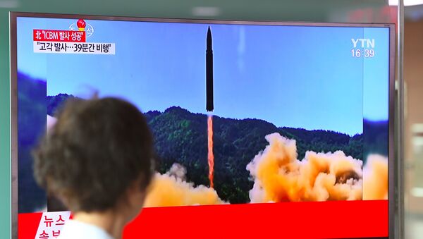 A woman walks past a television screen showing a picture of North Korea's launch of an intercontinental ballistic missile (ICBM), at a railway station in Seoul on July 4, 2017. - Sputnik International