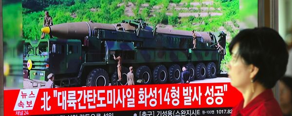 A woman walks past a television screen showing a picture of North Korea's launch of an intercontinental ballistic missile (ICBM), at a railway station in Seoul on July 4, 2017. - Sputnik International