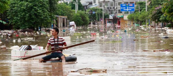 Man using an improvised flotation device to move through floodwaters on a flooded street in Liuzhou, Guangxi province Man using an improvised flotation device to move through floodwaters on a flooded street in Liuzhou, Guangxi province - Sputnik International