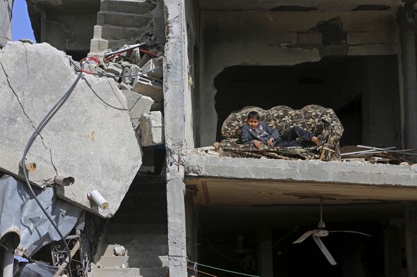 Mohammed Keferna, 14, sits on a couch in his family's building that was damaged by Israeli strikes during last summer's Israel-Hamas war, in Beit Hanoun, northern Gaza Strip, Friday, Jan. 30, 2015 - Sputnik International