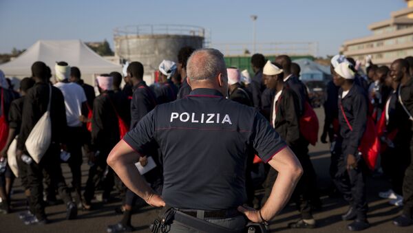 An Italian border police officer escorts sub Saharan men on their way to a relocation center, after arriving in the Golfo Azzurro rescue vessel at the port of Augusta, in Sicily, Italy, with hundreds of migrants aboard, rescued by members of Proactive Open Arms NGO, on Friday, June 23, 2017 - Sputnik International