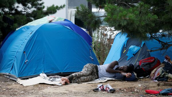 A migrant sleeps next to tents installed in a street near the entrance of the reception center for migrants and refugees at porte de La Chapelle, north of Paris, France, July 6, 2017 - Sputnik International