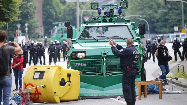 A German policeman stands in front of a barricade left by protesters in front of a police vehicle during the G20 summit in Hamburg, Germany, July 7, 2017 - Sputnik International