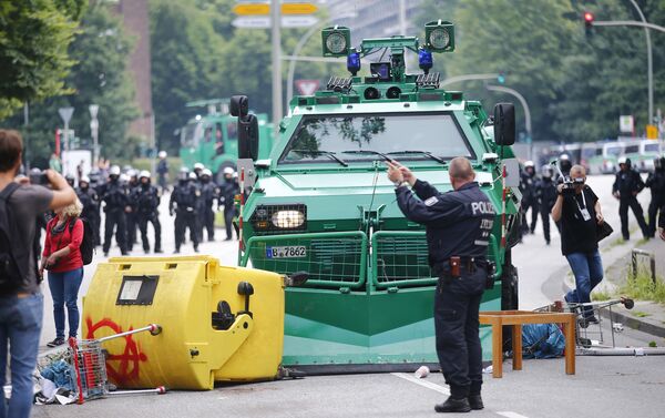 A German policeman stands in front of a barricade left by protesters in front of a police vehicle during the G20 summit in Hamburg, Germany, July 7, 2017 - Sputnik International