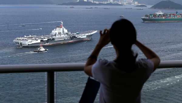 An onlooker takes a photo as China's aircraft carrier Liaoning sails into Hong Kong, China July 7, 2017 - Sputnik International