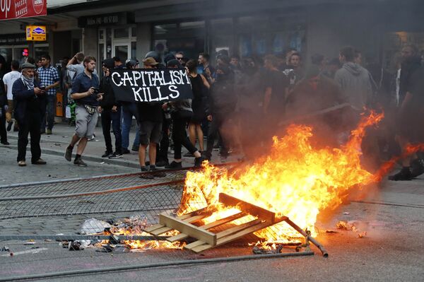 A protester holds a banner next to the bonfire during a demonstration at the G20 summit in Hamburg, Germany, July 7, 2017 A protester holds a banner next to the bonfire during a demonstration at the G20 summit in Hamburg, Germany, July 7, 2017 - Sputnik International