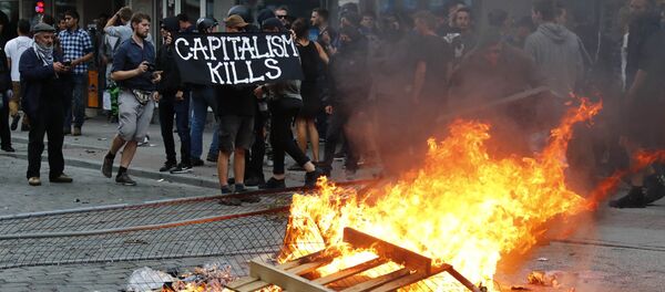 A protester holds a banner next to the bonfire during a demonstration at the G20 summit in Hamburg, Germany, July 7, 2017 - Sputnik International