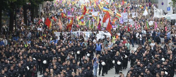 German riot police officers walk in front of protesters during demonstrations at the G20 summit in Hamburg, Germany, July 8, 2017 - Sputnik International