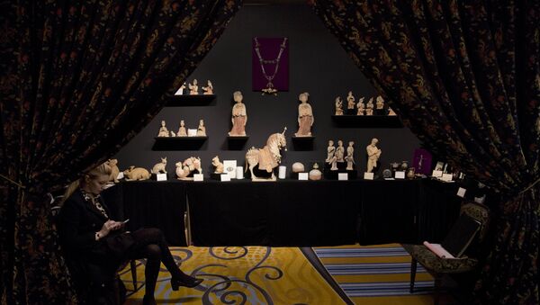 An exhibitor sits in a pottery antiquities stand before the doors open to the public at the fifth annual Mayfair Antiques and Fine Art Fair in London - Sputnik International