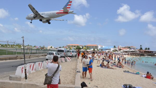 A plane lands at the Princess Juliana International Airport as beachgoers watch in Philipsburg, St. Maarten, a Dutch Caribbean territory, Thursday, July 13, 2017. On Wednesday, a New Zealand tourist was killed by the blast from a jetliner taking off when she was knocked into a wall as she tried to cling to a fence to feel the blast. - Sputnik International