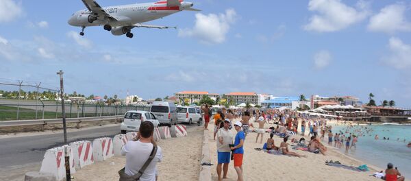 A plane lands at the Princess Juliana International Airport as beachgoers watch in Philipsburg, St. Maarten, a Dutch Caribbean territory, Thursday, July 13, 2017. On Wednesday, a New Zealand tourist was killed by the blast from a jetliner taking off when she was knocked into a wall as she tried to cling to a fence to feel the blast. - Sputnik International