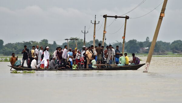 Villagers use a boat to cross a flooded road at Asigarh village in Morigaon district in the northeastern state of Assam, India, July 4, 2017 - Sputnik International