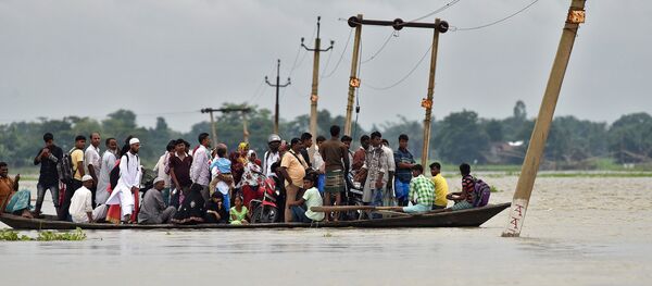 Villagers use a boat to cross a flooded road at Asigarh village in Morigaon district in the northeastern state of Assam, India, July 4, 2017 Villagers use a boat to cross a flooded road at Asigarh village in Morigaon district in the northeastern state of Assam, India, July 4, 2017 - Sputnik International