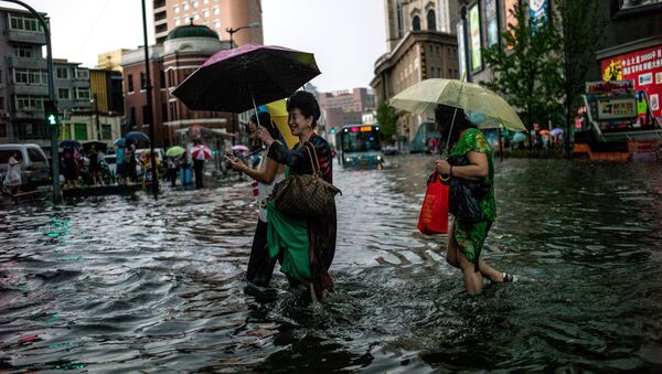 Women cross a flooded street after a heavy rain in Shenyang, Liaoning province on July 14, 2017 - Sputnik International