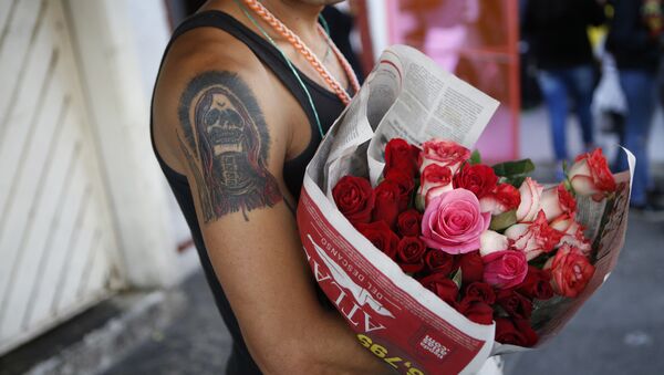 A tattooed devotee of La Santa Muerte, or Saint Death, sells flowers to devotees paying Day of the Dead visits to a well-known Santa Muerte altar in Tepito, Mexico City, Wednesday, Nov. 2, 2016 - Sputnik International