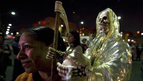 A devotee of the 'Santa Muerte' (Holy Death) holds a image as she prays at the shrine of the goddess at the Iztapalapa shantytown in Mexico City, on February 4, 2011. - Sputnik International
