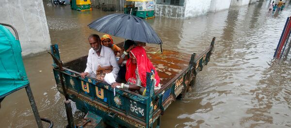 People sit in a tractor trolley as they move out of a flooded neighbourhood after heavy rain in Ahmedabad, India, July 24, 2017. - Sputnik International