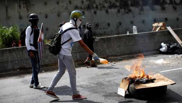 A demonstrator sets a roadblock on fire during a strike called to protest against Venezuelan President Nicolas Maduro's government in Caracas, Venezuela July 26, 2017. - Sputnik International