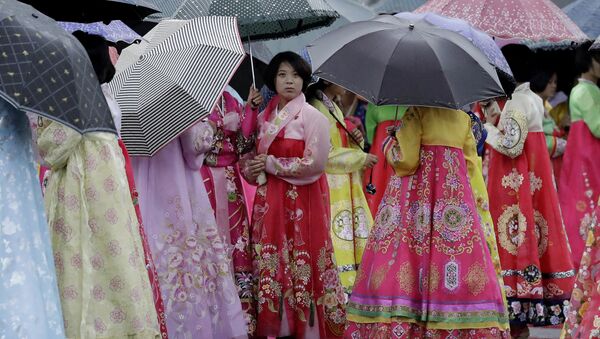 University students wearing traditional Korean dresses wait in the rain for the start of a mass dance on Thursday, July 27, 2017, in Pyongyang, North Korea as part of celebrations for the 64th anniversary of the armistice that ended the Korean War. - Sputnik International