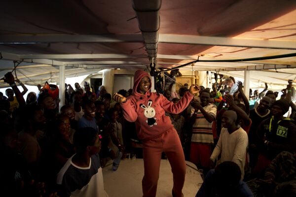 A woman from Nigeria dances on the deck of the Golfo Azzurro rescue vessel as it arrives at the port of Pozzallo, south of Sicily, Italy, with hundreds of migrants aboard, rescued by members of Proactive Open Arms NGO, on Saturday, June.17, 2017 A woman from Nigeria dances on the deck of the Golfo Azzurro rescue vessel as it arrives at the port of Pozzallo, south of Sicily, Italy, with hundreds of migrants aboard, rescued by members of Proactive Open Arms NGO, on Saturday, June.17, 2017 - Sputnik International