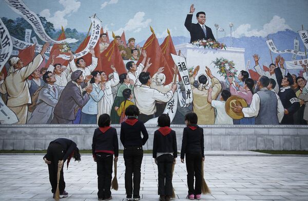 North Korean school girls holding brooms bow to pay their respects toward a mural which shows the late North Korean leader Kim Il-sung delivering a speech, before sweeping the area surrounding this mural on Tuesday, Dec. 1, 2015, in Pyongyang, North Korea North Korean school girls holding brooms bow to pay their respects toward a mural which shows the late North Korean leader Kim Il-sung delivering a speech, before sweeping the area surrounding this mural on Tuesday, Dec. 1, 2015, in Pyongyang, North Korea - Sputnik International