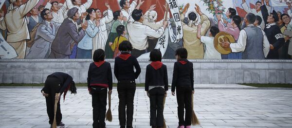 North Korean school girls holding brooms bow to pay their respects toward a mural which shows the late North Korean leader Kim Il-sung delivering a speech, before sweeping the area surrounding this mural on Tuesday, Dec. 1, 2015, in Pyongyang, North Korea - Sputnik International