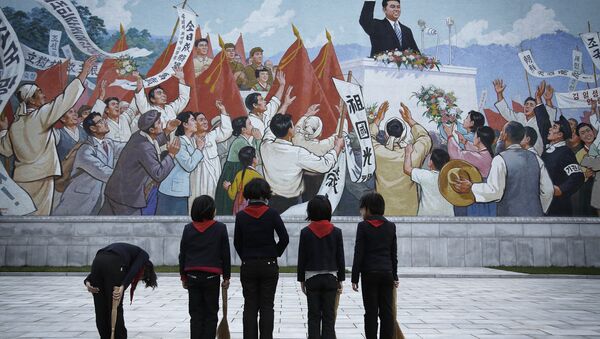 North Korean school girls holding brooms bow to pay their respects toward a mural which shows the late North Korean leader Kim Il-sung delivering a speech, before sweeping the area surrounding this mural on Tuesday, Dec. 1, 2015, in Pyongyang, North Korea - Sputnik International