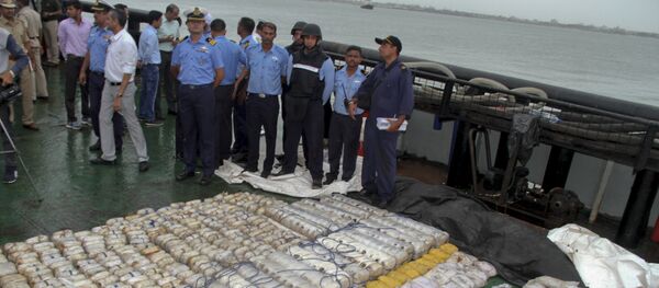 In this Sunday, July 30, 2017 photo, Indian coast guard officials, in blue, stand next to a massive amount of heroin they claim to have seized from a ship off the country's western coast near Porbandar, India - Sputnik International