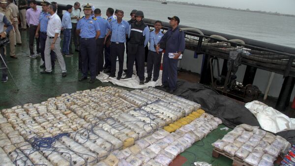 In this Sunday, July 30, 2017 photo, Indian coast guard officials, in blue, stand next to a massive amount of heroin they claim to have seized from a ship off the country's western coast near Porbandar, India - Sputnik International