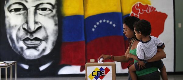 A woman holds her infant as she casts her vote in front of a mural of the late Venezuelan President Hugo Chavez at a polling station during the Constituent Assembly election in Caracas, Venezuela, July 30, 2017. A woman holds her infant as she casts her vote in front of a mural of the late Venezuelan President Hugo Chavez at a polling station during the Constituent Assembly election in Caracas, Venezuela, July 30, 2017. - Sputnik International