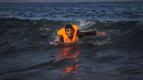 A migrant swims as he arrives on the island of Lesbos after crossing the Aegean sea from Turkey to Greece on an overcrowded inflatable boat , Tuesday, Oct. 27, 2015 - Sputnik International