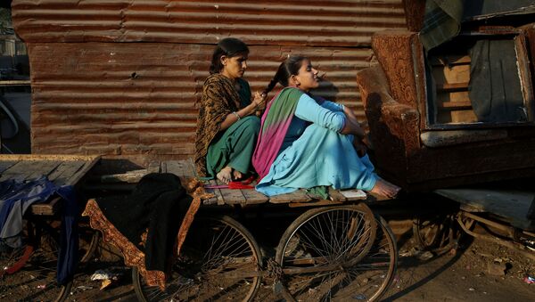 A woman ties the hair of her daughter into a braid as they sit on a cart before evening sets in at a poor neighborhood in New Delhi, India, Thursday, Dec. 5, 2013 - Sputnik International