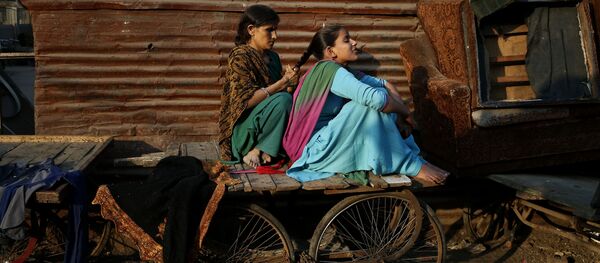 A woman ties the hair of her daughter into a braid as they sit on a cart before evening sets in at a poor neighborhood in New Delhi, India, Thursday, Dec. 5, 2013 - Sputnik International